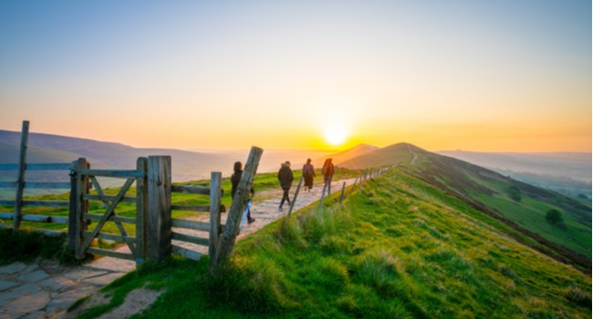hikers walking along a countryside path at sunrise