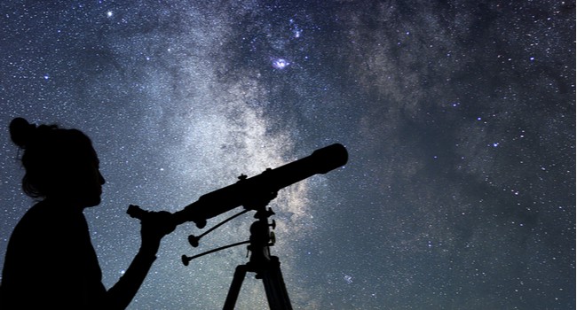 A woman with a telescope stargazing