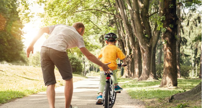 A father teaching his young son to ride a bike.