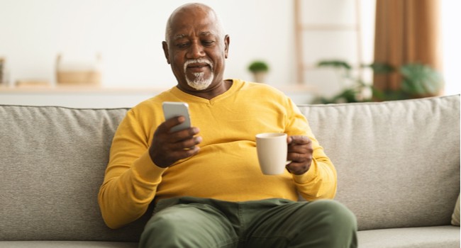 A man enjoying a cup of coffee and looking at his phone.