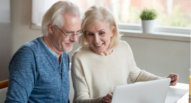 A mature couple looking at something together on a laptop.