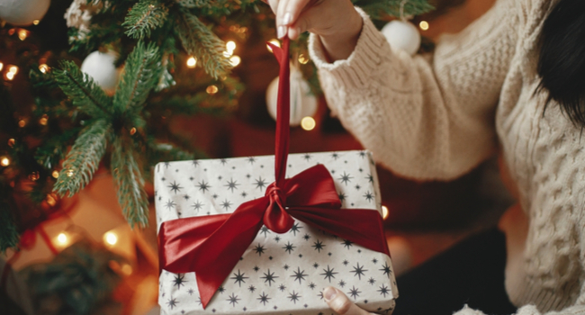A woman unwrapping a Christmas gift.